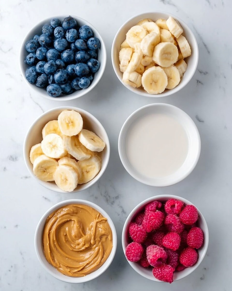 Five small white bowls are arranged on a white marbled surface, each filled with different ingredients. The top left bowl holds bright blue blueberries, the top right bowl contains white oat milk, the middle left bowl is full of sliced yellow bananas, the middle right bowl shows pink raspberries, and the bottom left bowl contains light brown peanut butter with a smooth texture. The colors contrast nicely against the white bowls and marbled background, showing a fresh and simple setup. Photo taken with an iphone --ar 4:5 --v 7