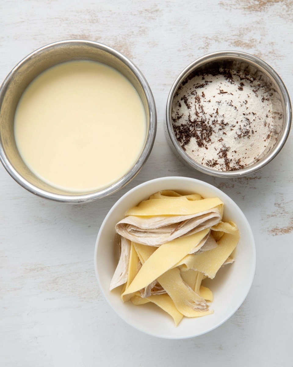 The image shows three bowls on a white marbled surface. The first bowl on the left is metal and filled with a creamy pale yellow liquid, smooth in texture. The second bowl at the top right is metal and contains a powdery white substance with dark brown bits spread throughout, giving it a spotted look. The third bowl in the center is white and holds pale yellow to light brown folded strips that look soft and slightly layered, resembling dough or pasta. photo taken with an iphone --ar 4:5 --v 7