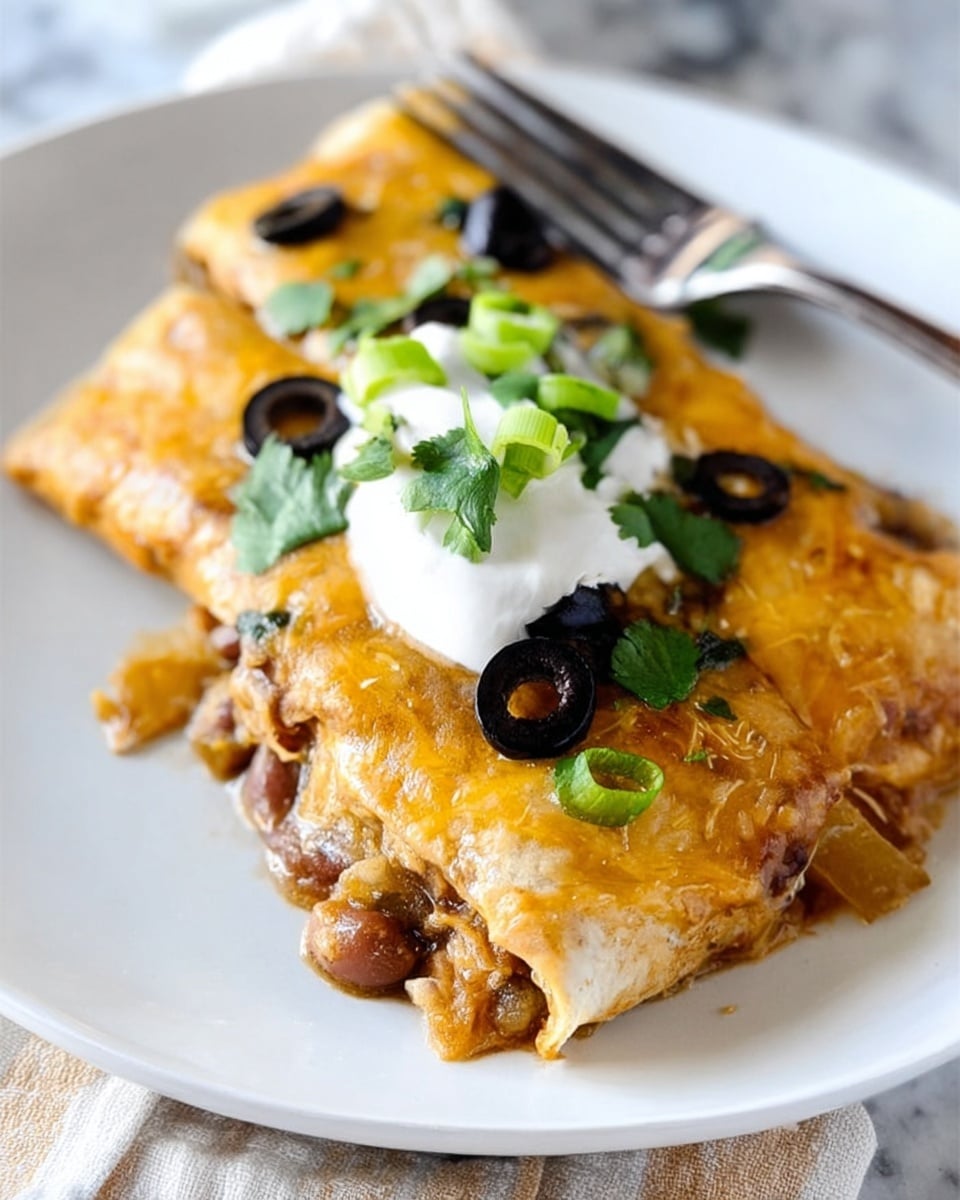 The image shows a folded enchilada on a white plate over a white marbled surface. The enchilada has a golden melted cheese layer covering its surface, with black olive slices scattered on top. Inside, you see a filling that looks like diced potatoes and beans. On top of the enchilada, there is a dollop of white sour cream with green chopped scallions and flat cilantro leaves as garnish. A fork is visible behind the enchilada. Photo taken with an iphone --ar 4:5 --v 7