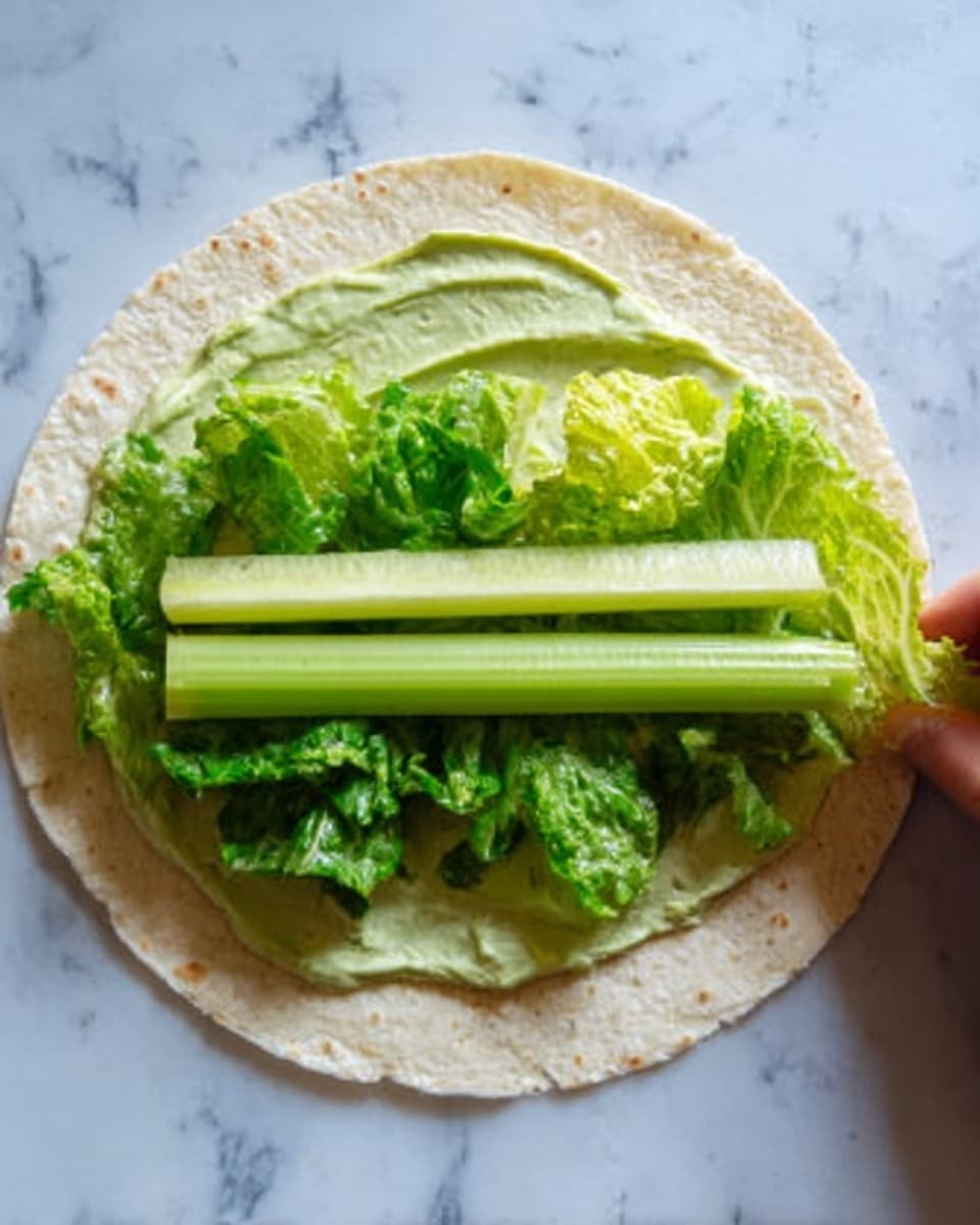 A close-up image showing a woman's hand holding a white tortilla wrap filled with layers of green lettuce, with a creamy light green sauce being poured from a glass bottle onto the wrap. The lettuce layers inside the wrap are tightly packed and fresh, showing different shades of green with a leafy texture. The sauce is thick and smooth, flowing steadily from the bottle. The background features a blurred wooden surface and a lemon half, all resting on a white marbled texture. photo taken with an iphone --ar 4:5 --v 7