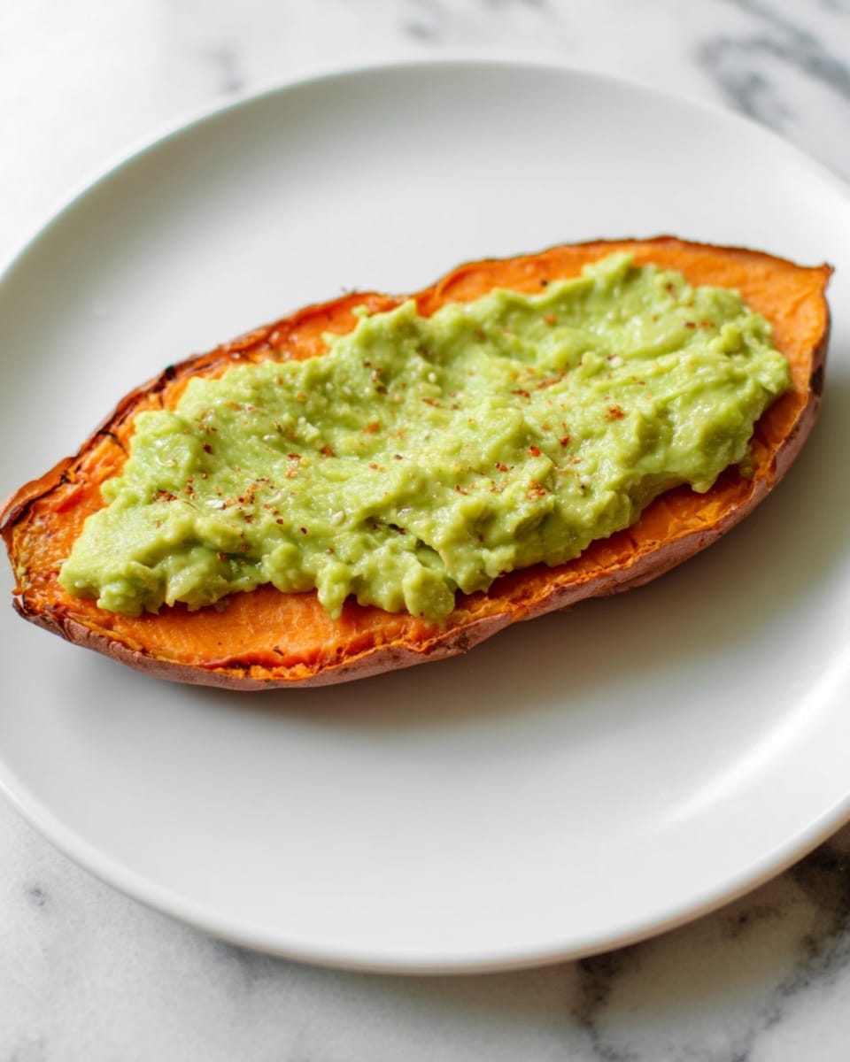 A single slice of roasted sweet potato lies flat on a white plate, with its orange flesh and slightly crispy, browned edges visible. On top, there is a smooth layer of light green avocado spread evenly across the sweet potato, showing a creamy texture with small bits and faint traces of seasoning. The plate sits on a white marbled surface. photo taken with an iphone --ar 4:5 --v 7