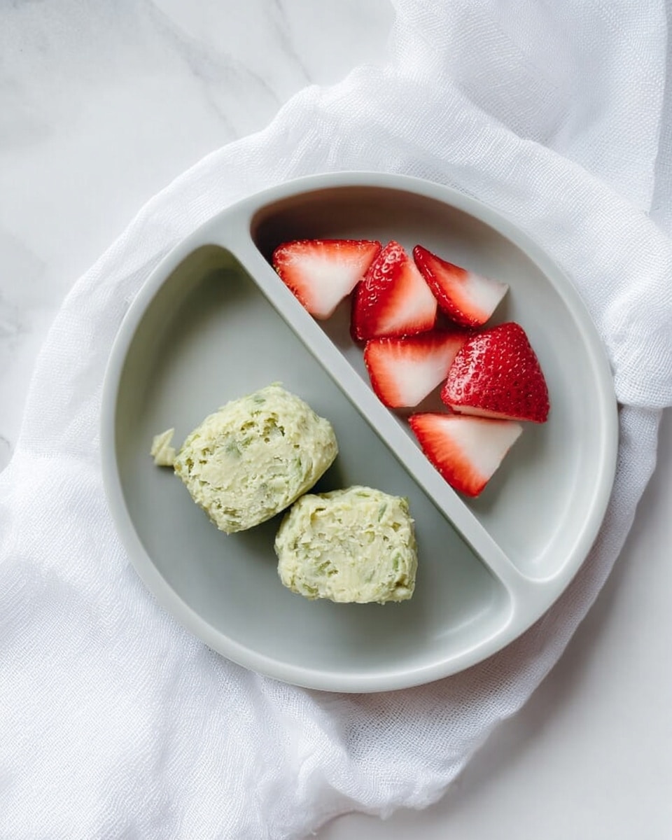 A round white plate with three sections sits on a white marbled surface with a white cloth nearby; the largest section holds two large, soft, unevenly shaped greenish pieces with a textured, creamy look, while a smaller section contains five bright red strawberry slices with white inner parts, arranged neatly. Photo taken with an iphone --ar 4:5 --v 7
