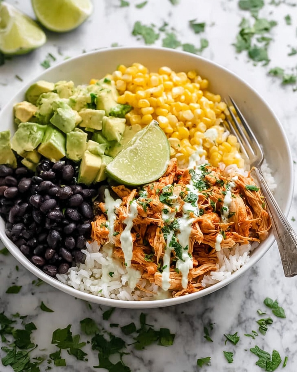 A white bowl filled with four sections of food on top of a bed of white rice; the sections include black beans on the left, bright yellow corn on the right, diced green avocado pieces in the top left, and shredded orange chicken with a light drizzle of white sauce sprinkled with chopped green herbs in the center, accompanied by a wedge of lime resting on the rice near the chicken; a metal fork is placed on the right side of the bowl, all set on a white marbled surface with some scattered green herb leaves around, photo taken with an iphone --ar 4:5 --v 7