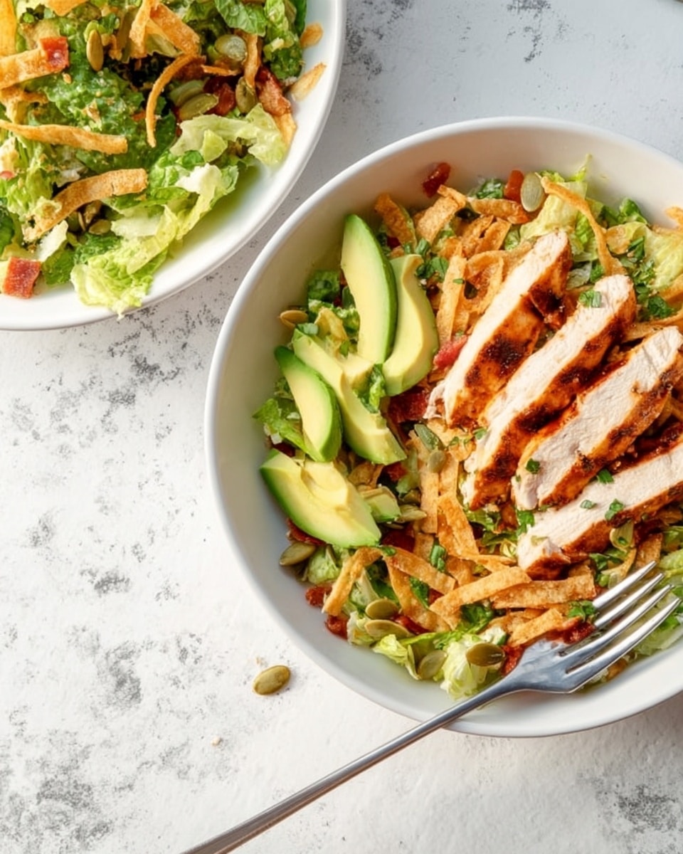 The image shows two white bowls on a white marbled surface. One bowl contains a salad made of green lettuce, thin golden crispy strips, slices of avocado with smooth bright green texture, and small bits of red tomato, topped with pumpkin seeds. The other bowl has a similar salad but additionally includes four thick slices of grilled chicken placed neatly on one side, showing a golden brown grilled texture with visible grill marks and some chopped green herbs sprinkled on top. A fork is resting in the bowl with chicken. The colors are fresh and vibrant with greens, yellows, reds, and browns contrasting nicely. photo taken with an iphone --ar 4:5 --v 7