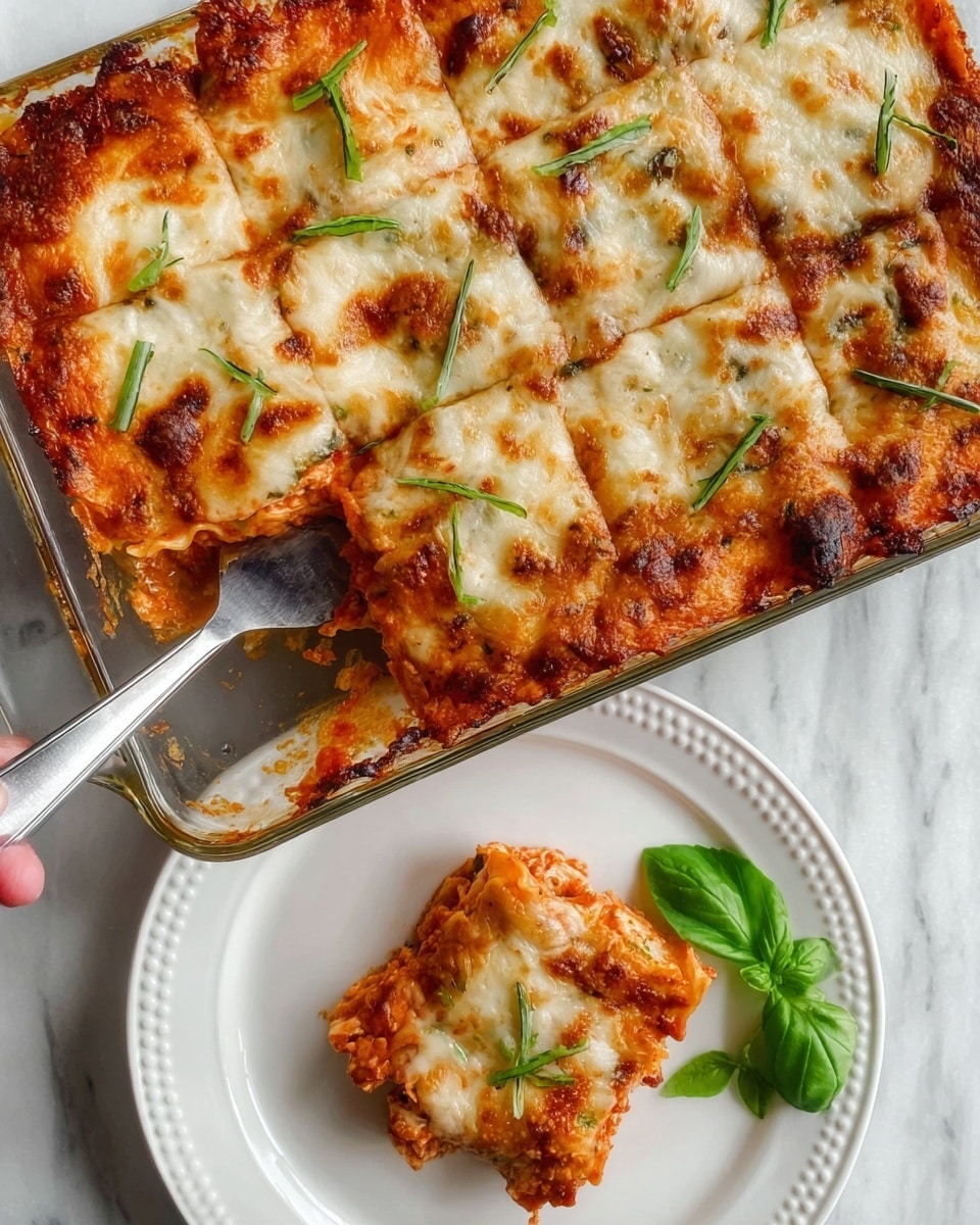 A clear glass rectangular dish filled with a baked lasagna topped with melted, bubbly cheese showing a light golden color and some browned spots, garnished with thin green basil strips scattered on top. One square piece is being served with a metal spatula, showing layers beneath the cheese: a rich red tomato sauce and a thick pasta layer with a slightly rough texture. The single lasagna piece is placed on a white round plate with a dotted rim, garnished with two bright green fresh basil leaves. The scene is set on a white marbled surface, and a woman's hand is holding the spatula to serve the slice. photo taken with an iphone --ar 4:5 --v 7