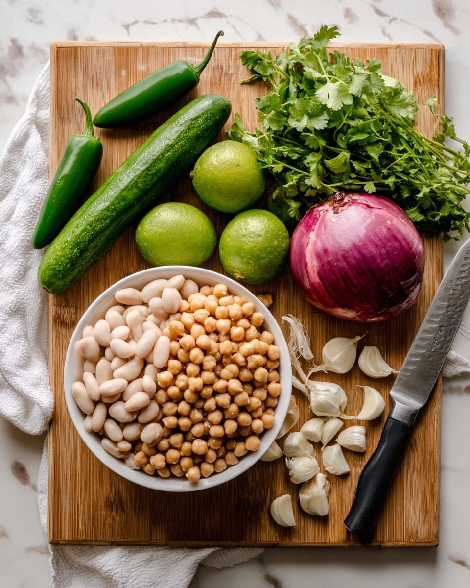 A wooden cutting board sits on a white marbled surface with fresh ingredients neatly arranged. In the center, there is a white bowl filled with two layers of beans: white beans on the bottom and round, light brown chickpeas piled on top, showing smooth and slightly shiny textures. On the left side of the board, three green jalapeño peppers lie horizontally above two bright green limes and a long, dark green cucumber placed vertically. Near the limes, there are several peeled white garlic cloves scattered. On the top right corner of the board, a whole large purple onion rests beside a bunch of fresh green cilantro, which spreads outward with delicate leaves. A large silver knife with a black handle is placed beside the cilantro on a white cloth. photo taken with an iphone --ar 4:5 --v 7