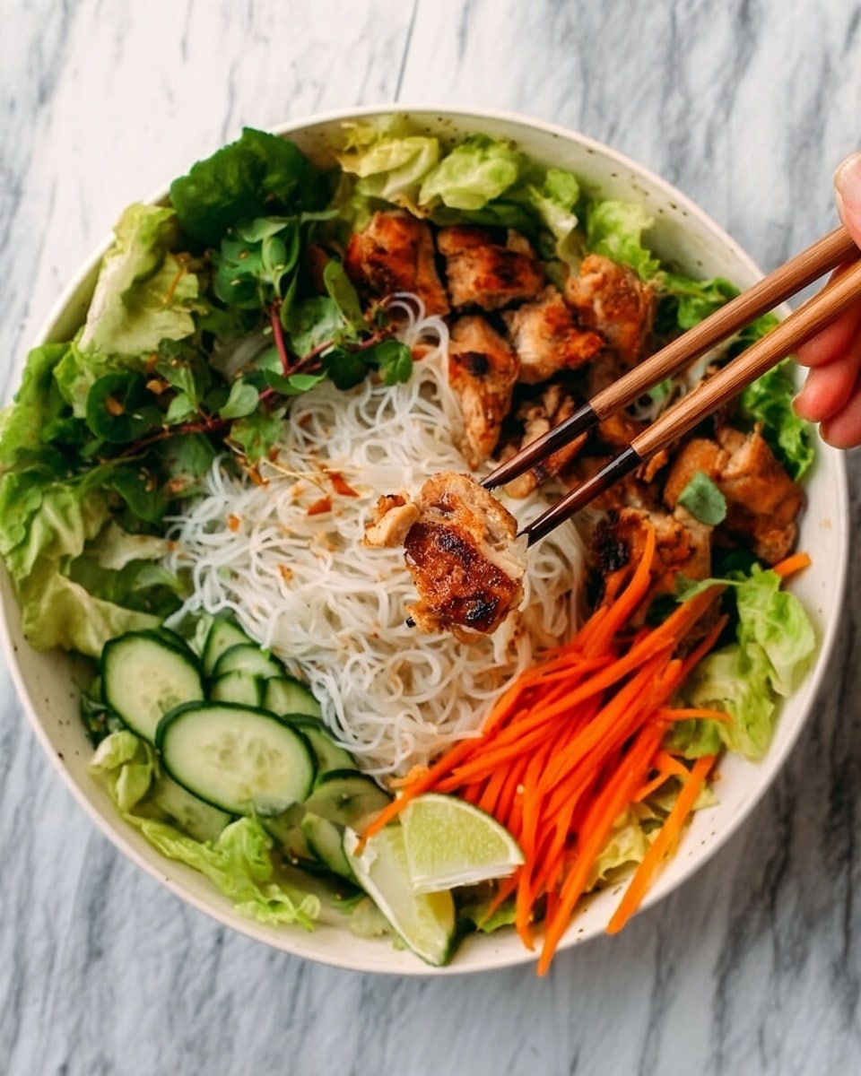A white bowl filled with layers of fresh green lettuce and herbs at the bottom, topped with bright orange carrot sticks and dark green cucumber slices on one side. On the other side, thin white rice noodles create a soft base layer, with golden brown grilled chicken pieces resting on top. A wedge of lime sits near the edge, adding a pop of light green color. A woman's hand holding wooden chopsticks lifts a piece of the grilled chicken with some noodles. The bowl is set on a white marbled surface. photo taken with an iphone --ar 4:5 --v 7