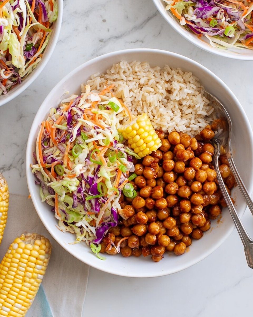 A white bowl with three layers: the bottom layer is light brown rice, the right side is filled with shiny, cooked brown chickpeas, and the top left holds a colorful coleslaw with shredded light green cabbage, orange carrots, purple cabbage, and green onions. A small yellow and white corn cob piece is placed on the rice near the coleslaw. A silver spoon rests on the edge of the bowl. The bowl sits on a white marbled surface with parts of another bowl and corn cob visible nearby. photo taken with an iphone --ar 4:5 --v 7