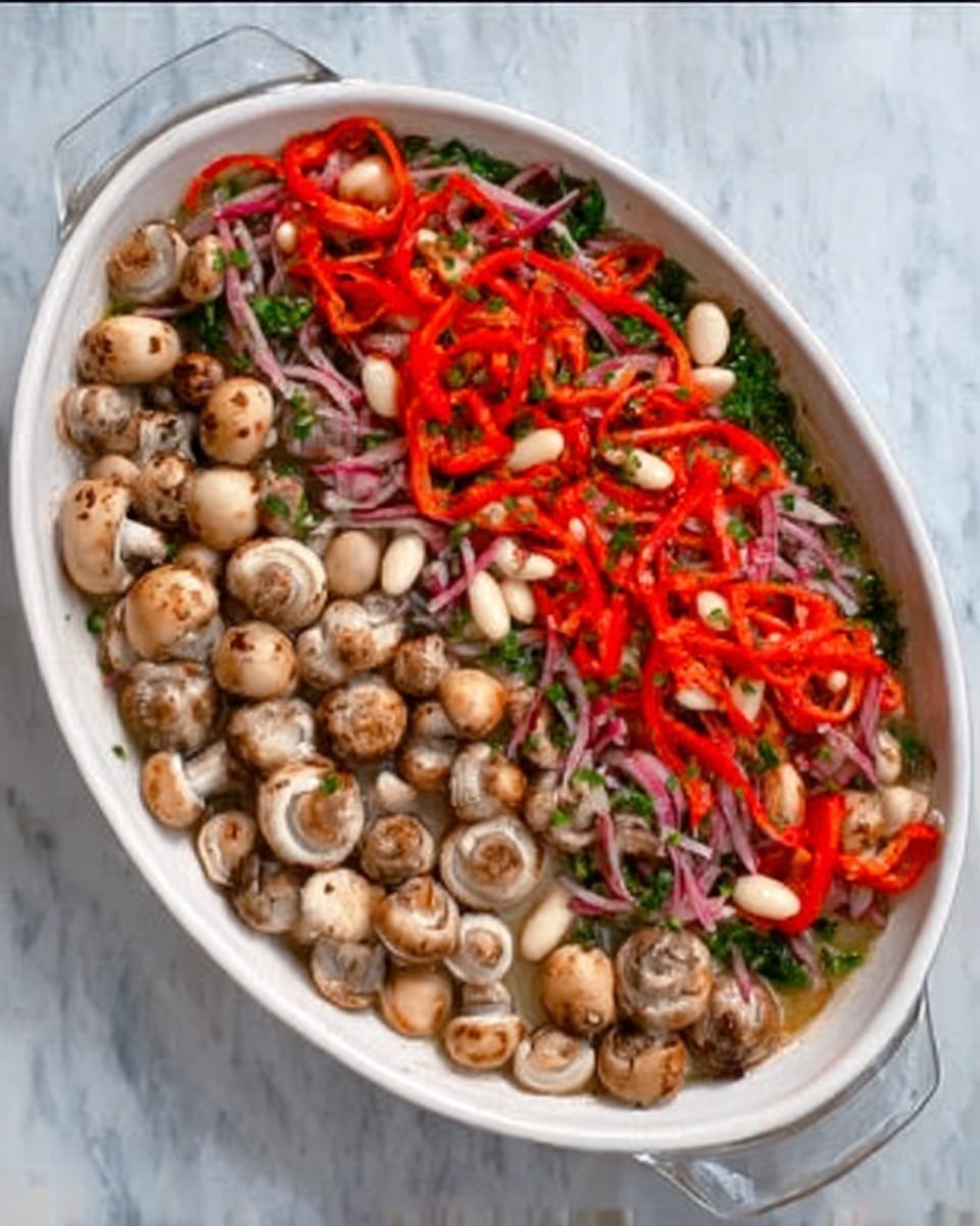 A white oval dish filled with a layer of small whole mushrooms, light beige with brown spots, covering the bottom. On top of the mushrooms, there is a colorful mix of thin red pepper strips, small white beans, and thin slices of red onion, all spread evenly across the surface. The dish is placed on a white marbled surface. photo taken with an iphone --ar 4:5 --v 7